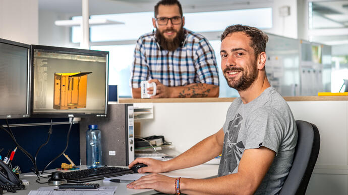 Two people with designs on computer screen