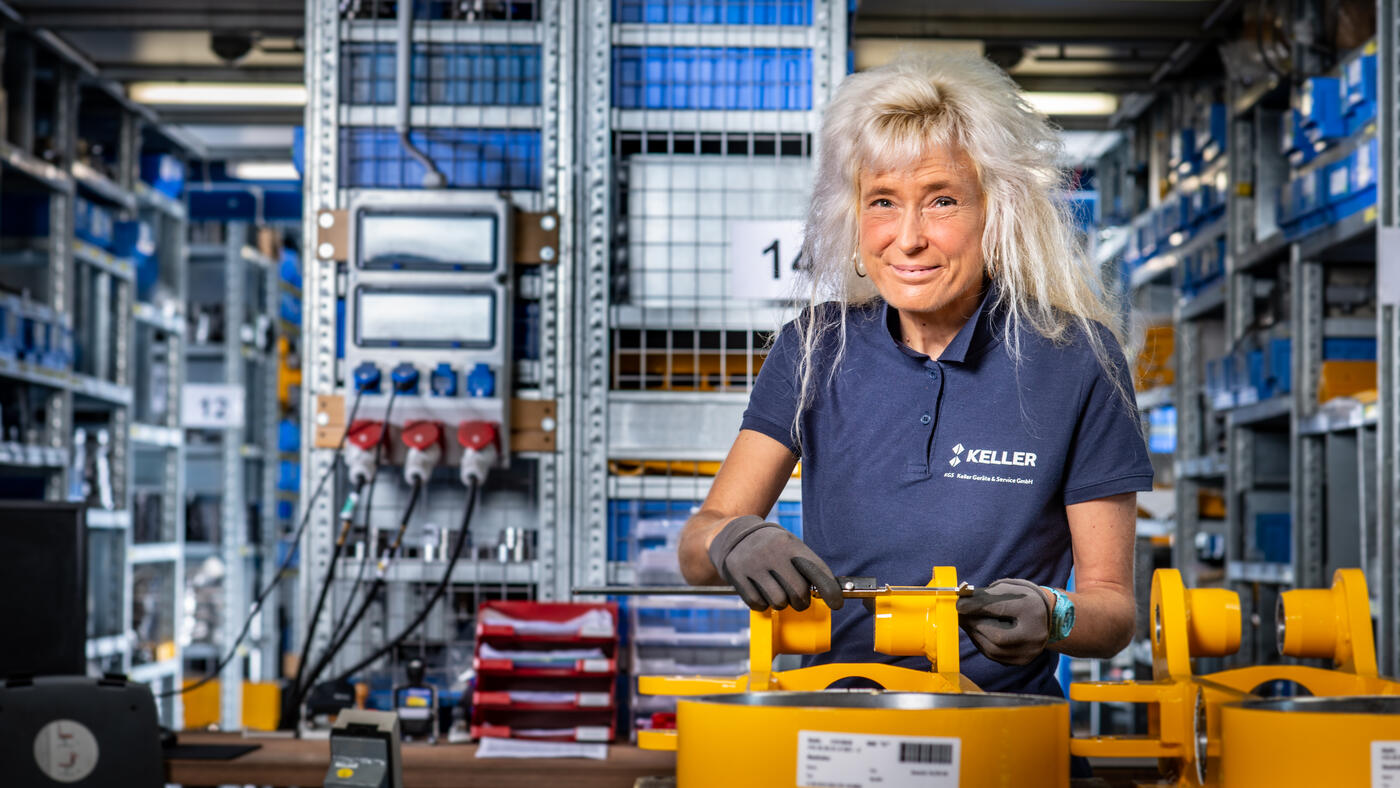 Eine Mechanikerin kontrolliert die Maße eines Bauteils. Sie arbeitet in der Qualitätssicherung.