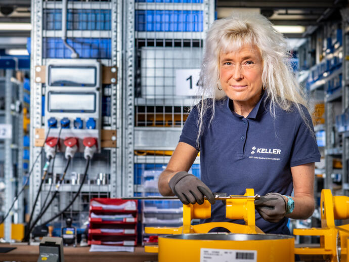 Eine Mechanikerin kontrolliert ein Bauteil, um die Maße zu prüfen.